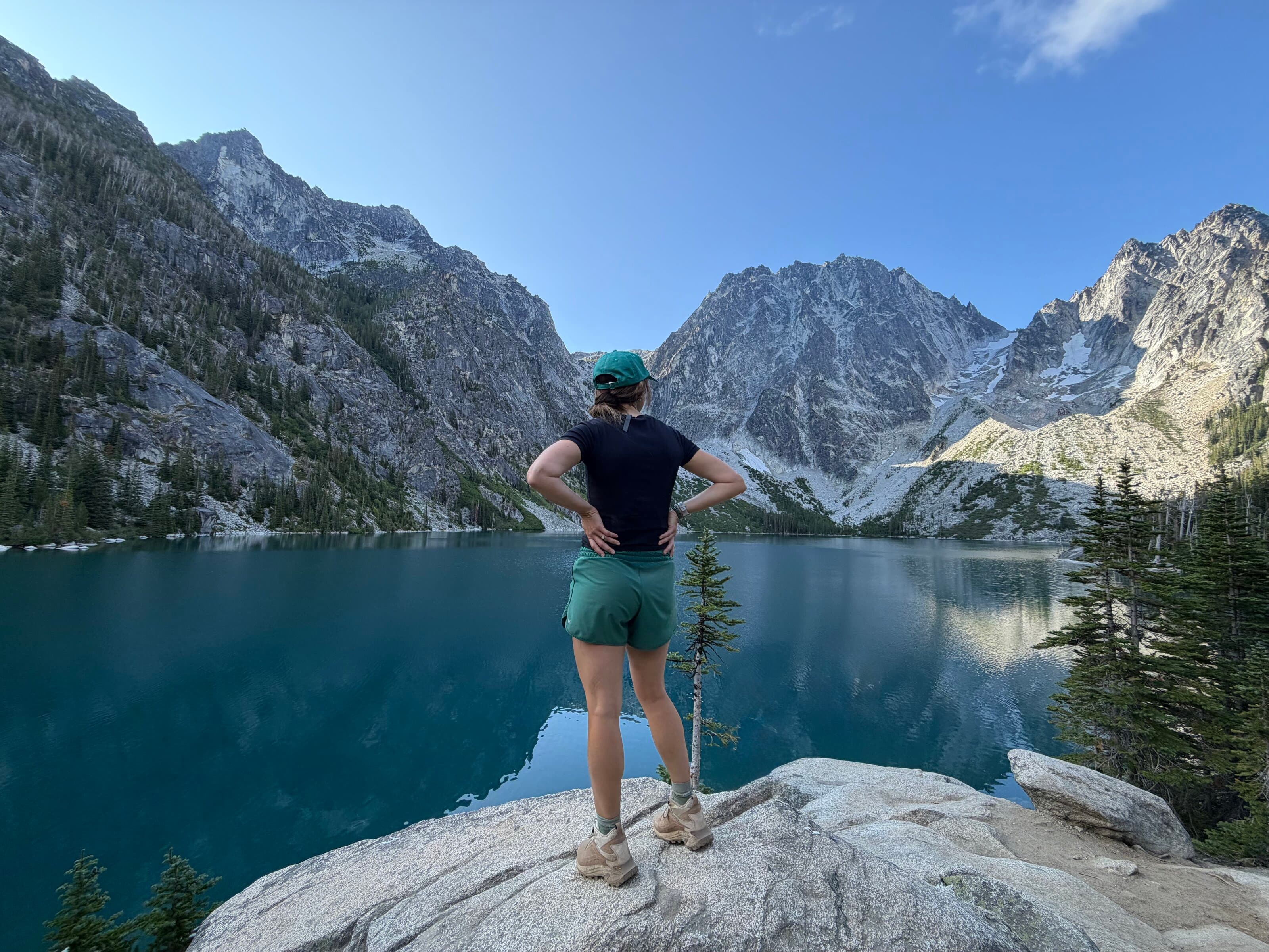 A woman looking out over an alpine lake below granite peaks
